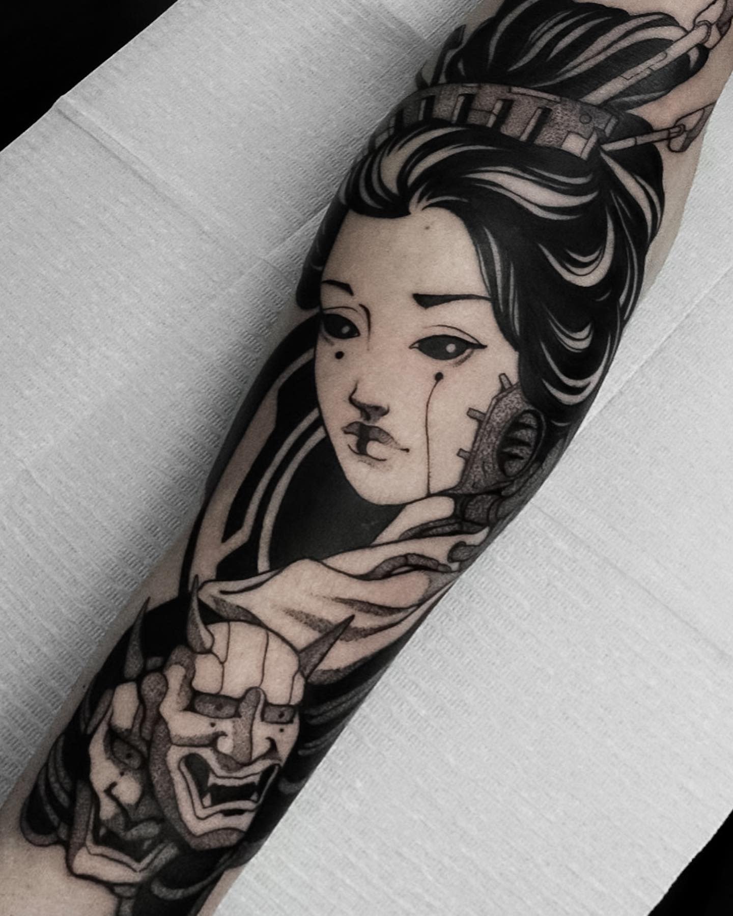 Cyberpunk tattoo featuring a geisha with mechanical details and traditional Japanese masks, blending modern and traditional elements on the forearm